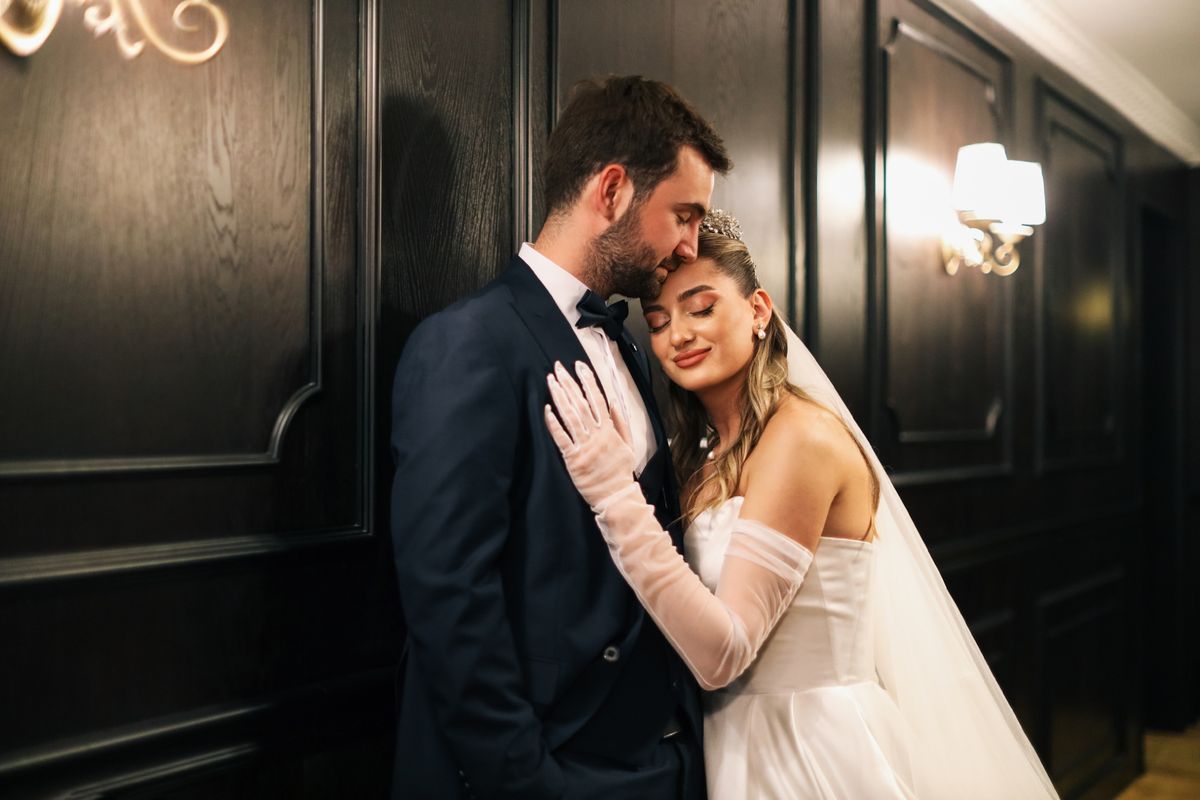 Los novios comparten un abrazo íntimo junto a una pared de madera oscura